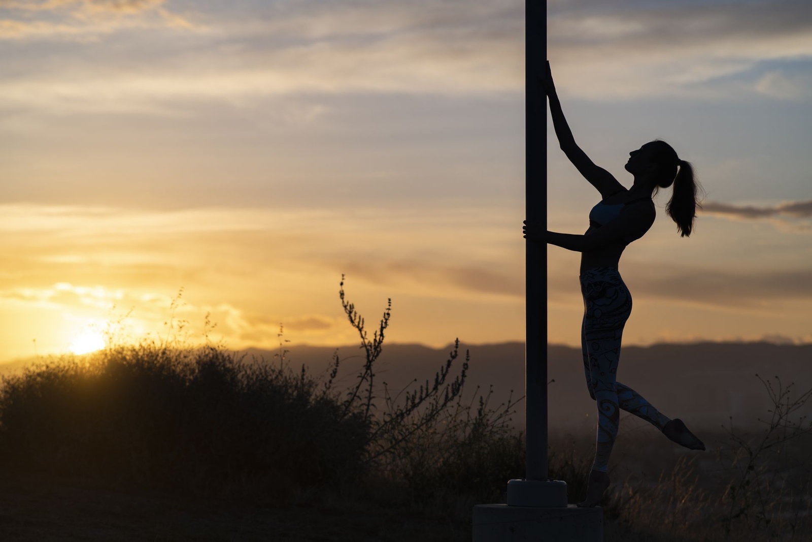 Danseuse contre un poteau au soleil couchant
